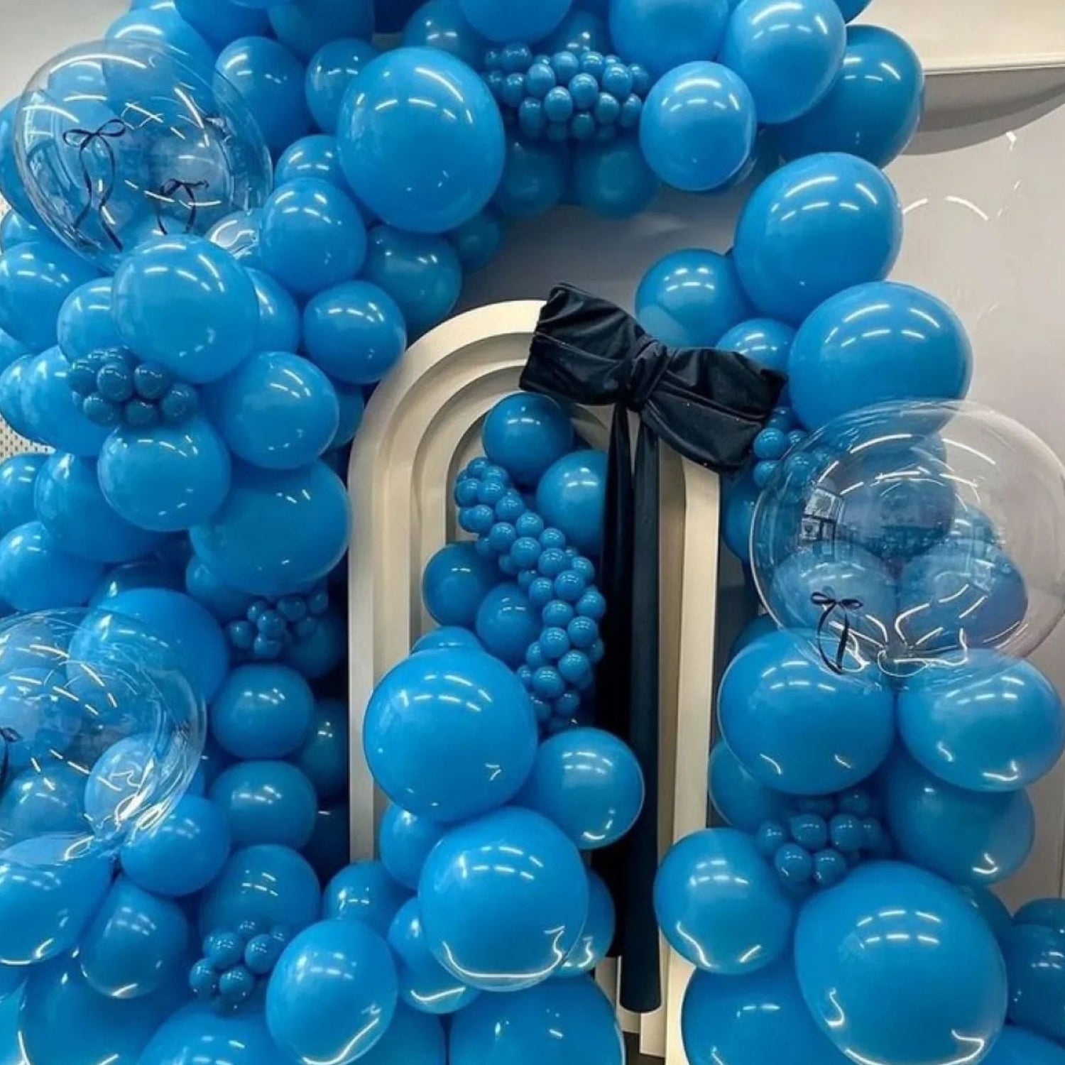 Vibrant blue balloon garland with clear balloons and a large black bow, perfect for kids' celebrations